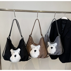 Detailed view of plush puppy tote bags in black brown and grey colors hanging on a rack