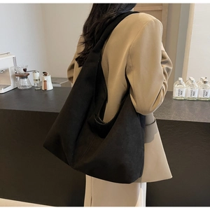 Vue détaillée d'un grand sac hobo noir mat porté par un mannequin dans un café branché