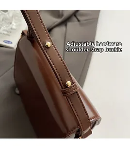 Detail of dark brown leather handbag with adjustable gold hardware shoulder strap buckle