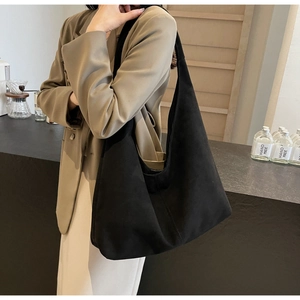 Mannequin portant un grand sac hobo noir mat dans un décor de café minimaliste