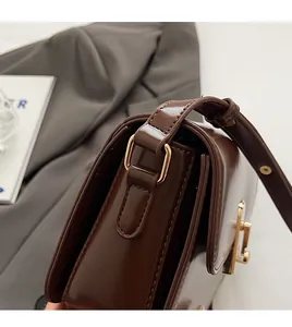 Detail view of dark brown leather crossbody bag with premium gold-tone D-ring hardware