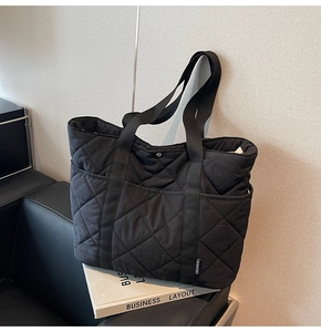 Détail du sac cabas matelassé noir montrant le motif en losanges et l'étiquette