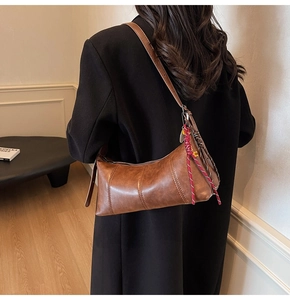 Close-up of retro brown textured leather underarm bag with decorative woven rope strap