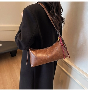 Brown leather crescent shoulder bag with woven rope detail shown on model shoulder