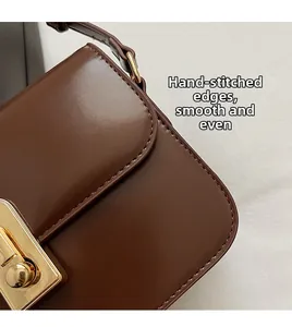 Detail of hand-stitched edging and golden buckle on vintage brown leather crossbody bag