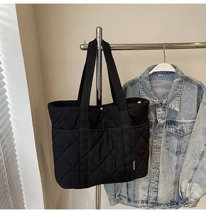 Détail du sac cabas matelassé noir avec surpiqûres en losange et larges anses tissées