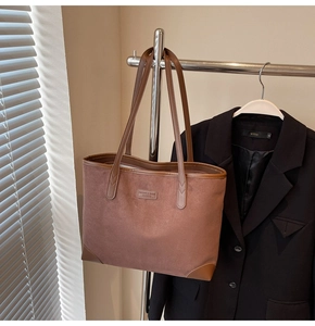 Detail einer braunen Wildleder-Tragetasche mit Ledergriffen in eleganter Hängepräsentation