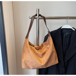 Detail der hobo-tasche aus camelfarbenem wildleder mit braunem lederriemen und metallbeschlägen