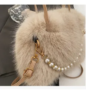 Dettaglio borsa beige in ecopelliccia con chiusura in metallo oro e tracolla di perle