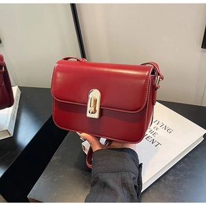 Detail of red leather crossbody bag featuring a gold rectangular twist lock closure