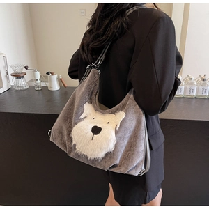 Detail of grey shoulder tote bag with a white fuzzy dog pattern in a minimalist cafe
