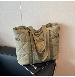 Détail du sac fourre-tout matelassé vert olive avec surpiqûres et étiquette de marque