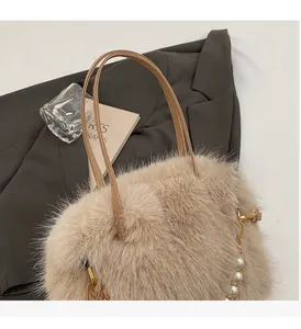Dettaglio della borsa beige in peluche con catena di perle e fibbia dorata su un blazer