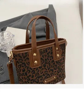 Détail du sac cabas léopard avec bordure en cuir marron et rivets dorés brillants
