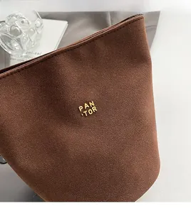 Makroaufnahme einer braunen Beuteltasche aus mattem Leder mit goldenem Metalllogo