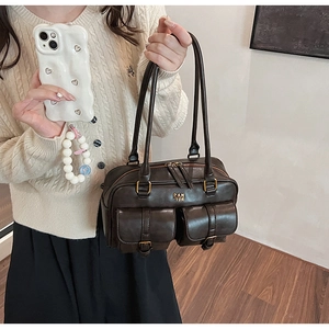 Detailed view of the dark brown leather texture and gold hardware on the commuter bag