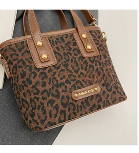 Détail d'un sac seau léopard avec rivets dorés et poignées en cuir marron