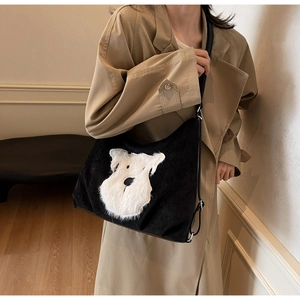 Detail of black corduroy shoulder bag featuring a white plush Schnauzer patch