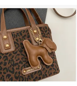 Détail du sac seau imprimé léopard avec anse en cuir et breloque chien élégante