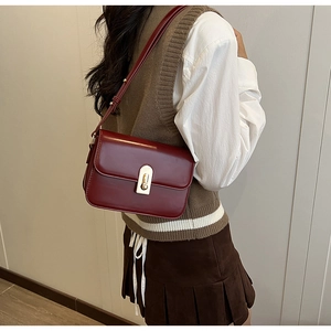 Detail of dark red vintage crossbody bag with gold metal clasp and adjustable strap