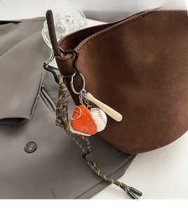 Nahaufnahme eines dreiteiligen Baseball-Schlüsselanhängers an einer braunen Wildledertasche