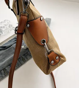 Dettaglio della borsa in tela kaki con rinforzi in pelle marrone e fibbie in metallo scuro
