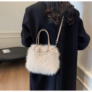 Dettaglio borsa a secchiello in peluche beige con manico di perle su cappotto nero