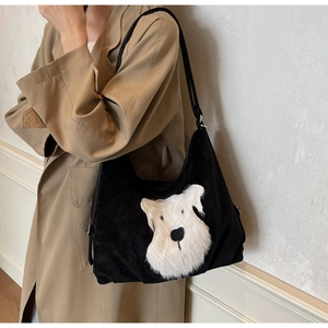 Close-up of black corduroy tote bag featuring a cute white plush dog patch detail