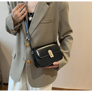 Detail shot of a black leather crossbody bag with a gold twist-lock on a stylish model