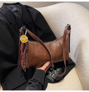Detail of vintage brown underarm bag with leather texture and smiley face pendant