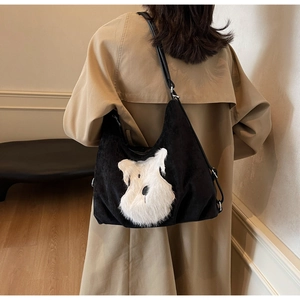 Detail of corduroy shoulder bag with plush schnauzer patch on a model wearing a beige coat