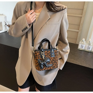 Détail du mini sac seau léopard avec poignée noire et breloque en forme de chiot