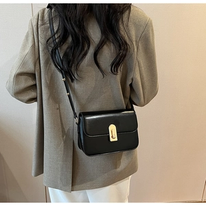 Detailed view of black leather crossbody bag with elegant gold metal twist lock buckle