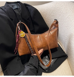 Brown retro leather underarm bag with vertical stitching and yellow smiley charm detail