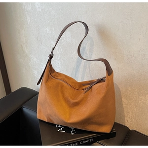 Detailansicht der hobo-tasche aus wildleder mit lederriemen auf schwarzem sofa