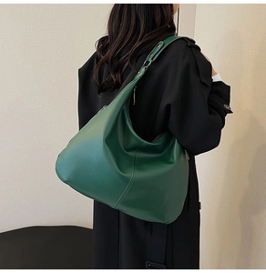 Dunkelgrüne Hobo-Tasche aus strukturiertem Leder getragen zum schwarzen Trenchcoat
