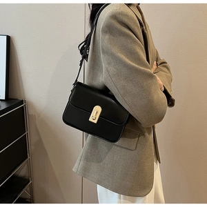 Detail of a vintage black leather crossbody bag with a gold exclamation mark buckle
