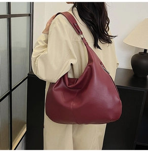Dunkelrote Hobo-Tasche aus Lederimitat mit Kieselstruktur getragen zum beigen Trenchcoat