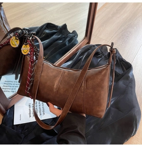 Detail of vintage brown suede shoulder bag with smiley charms and metal zipper close-up