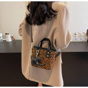 Détail du sac seau léopard avec poignées noires et pendentif en forme de chien