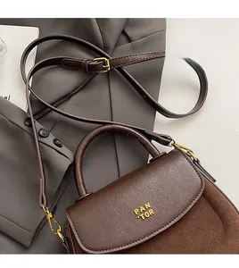 Detail of the brown contrast leather handbag with golden buckle on a grey blazer