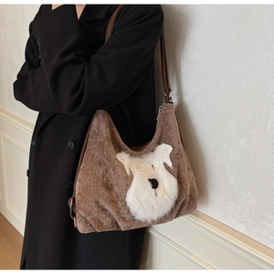 Detail of a brown suede tote bag featuring a cute white plush schnauzer dog patch