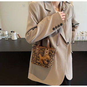 Détail du sac seau à imprimé léopard avec bandoulière en cuir brun et breloque chien