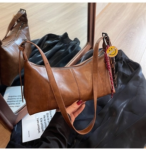 Detail view of brown vintage underarm bag with silver zipper and smiley face charm decoration
