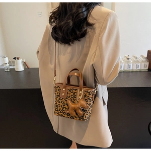 Détail du sac seau léopard avec bandoulière en cuir marron et breloque en forme de chien