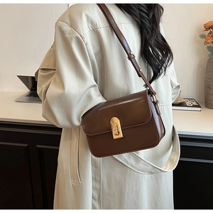 Detailed view of deep brown leather crossbody bag with golden metal swivel lock and strap