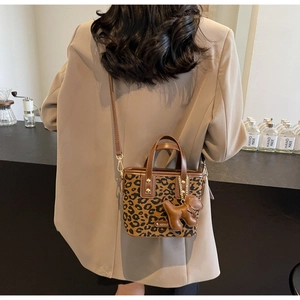 Détail du sac seau léopard avec bordure en cuir marron et pendentif chiot mignon