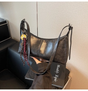 Detail of vintage black leather shoulder bag with decorative Smiley tag and braided rope
