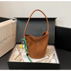 Nahaufnahme braune Wildleder-Beuteltasche mit Gold-Logo und Anhängern in Geschenkbox