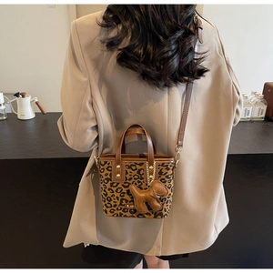 Détail du sac seau à motif léopard avec un pendentif chien en cuir brun et bandoulière